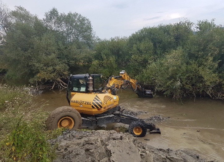 Ein Bagger gräbt ein Loch in einen Bach.