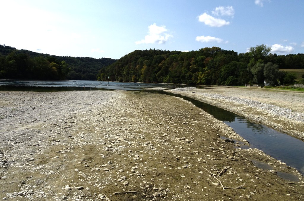 Kiesbank an einem Fluss während Trockenheit und niedriger Wasserführung.